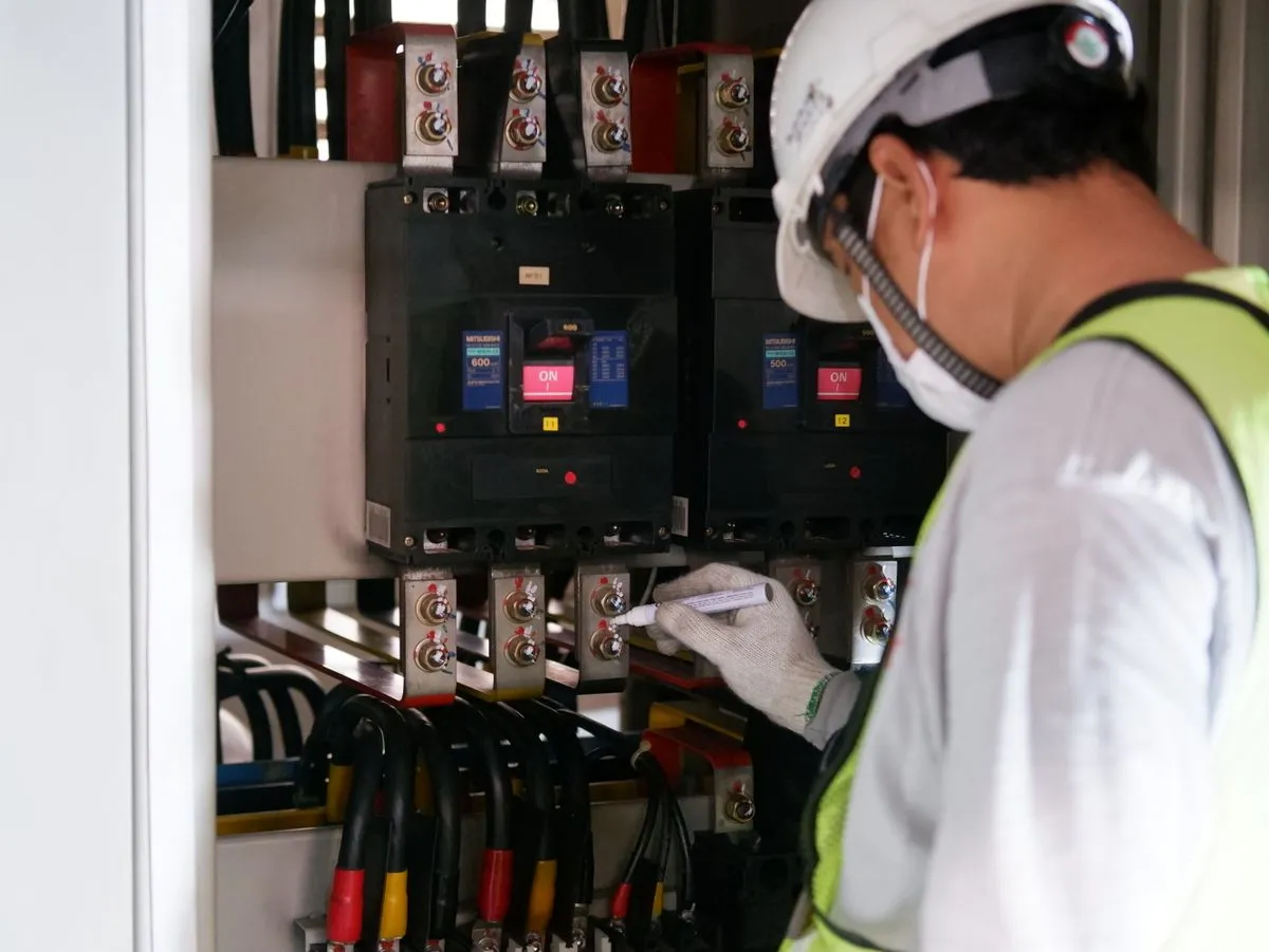 Technician examining circuit protection equipment inside a panel