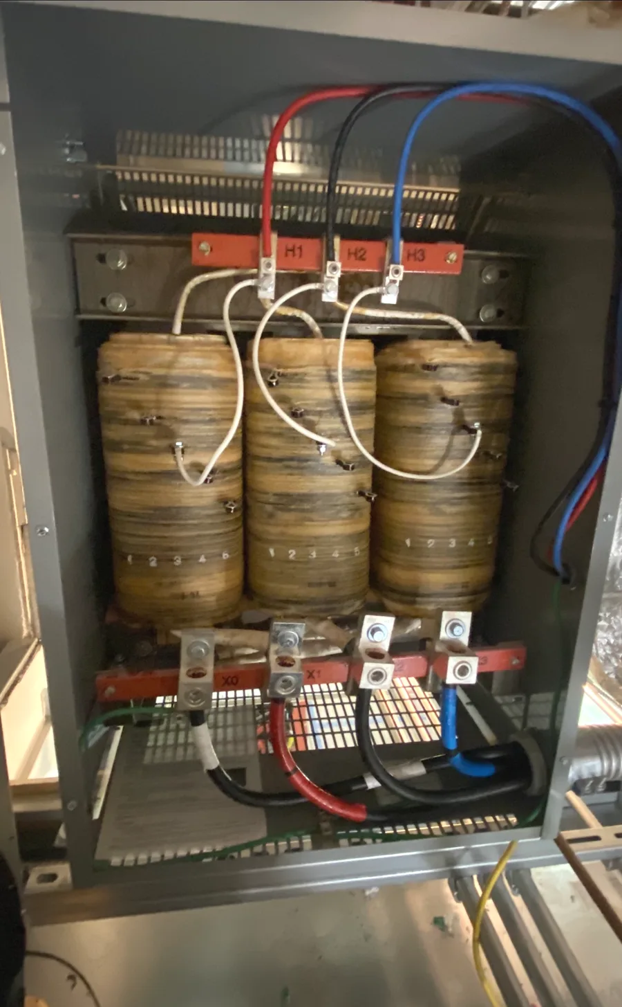 Three coils and labelled terminals inside an open dry-type transformer