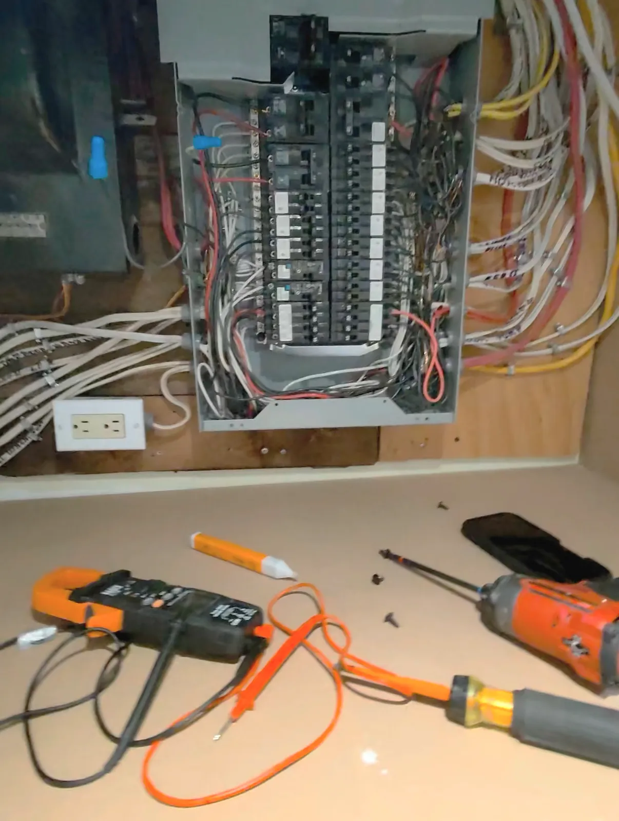 Clamp meter, voltage tester and hand tools laid out during electrical troubleshooting at an open breaker panel in Toronto