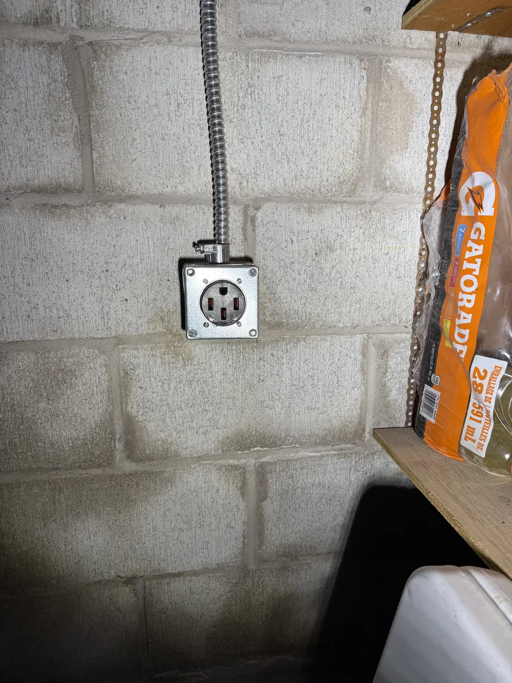 A 240 volt NEMA 14-50 receptacle for an EV charger, fed in flexible metal conduit on a concrete block wall, installed by Portman Electric