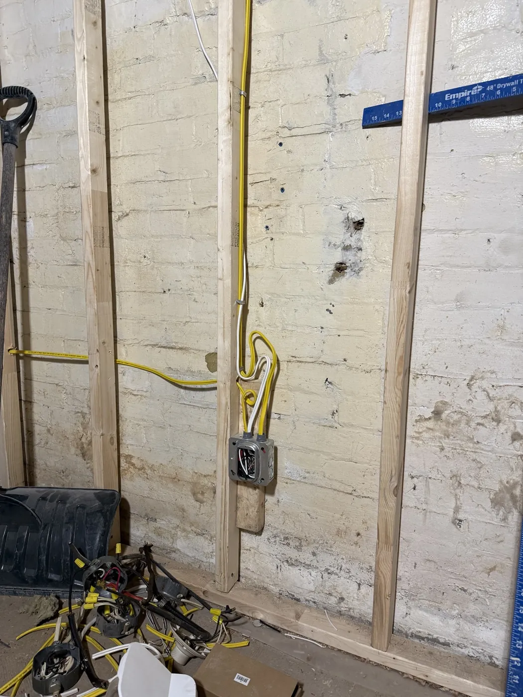 New branch-circuit wiring and a device box run against the original brick wall of a Kensington Market home.