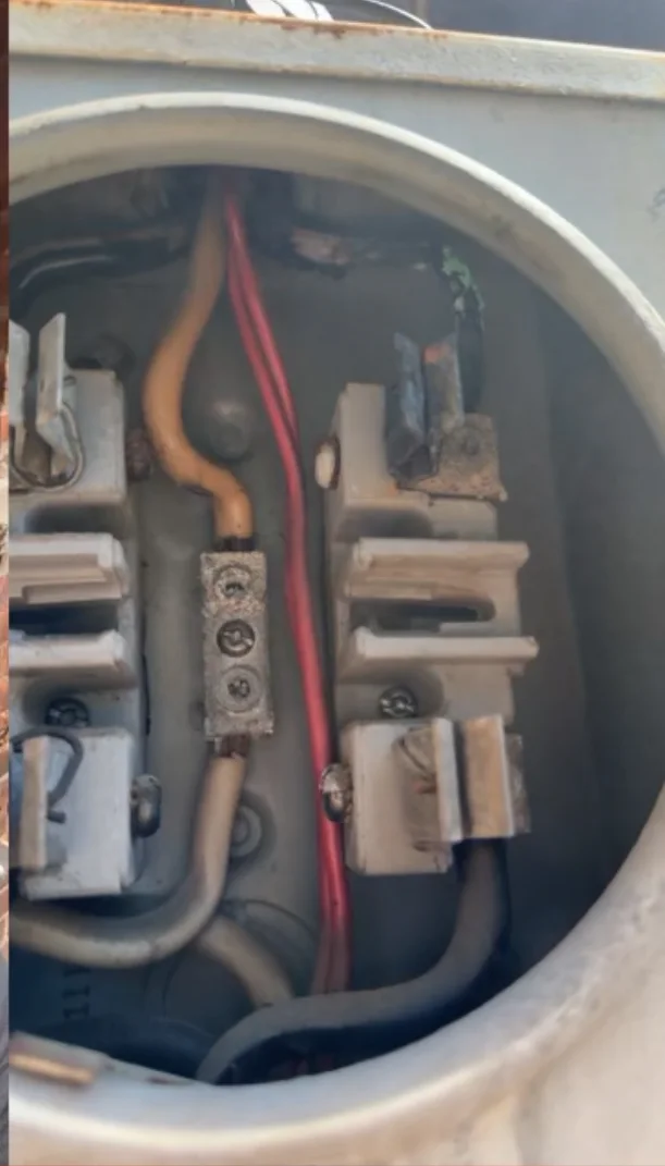 Close-up inside the damaged meter socket showing a heat-damaged terminal, charred insulation and corroded service connections.