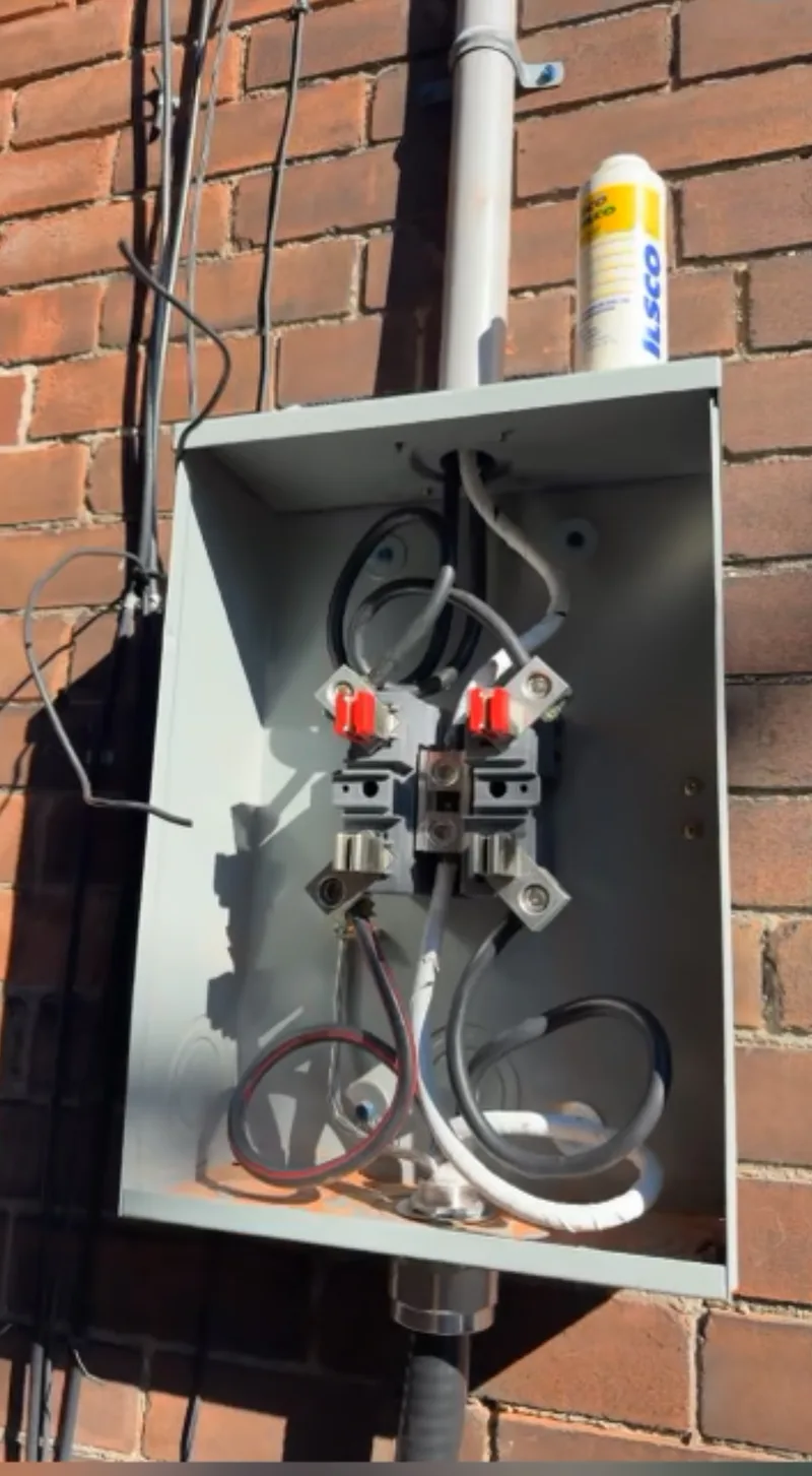 Replacement meter base mounted on the brick exterior of a Toronto home, with the new service conductors being made up during the installation.