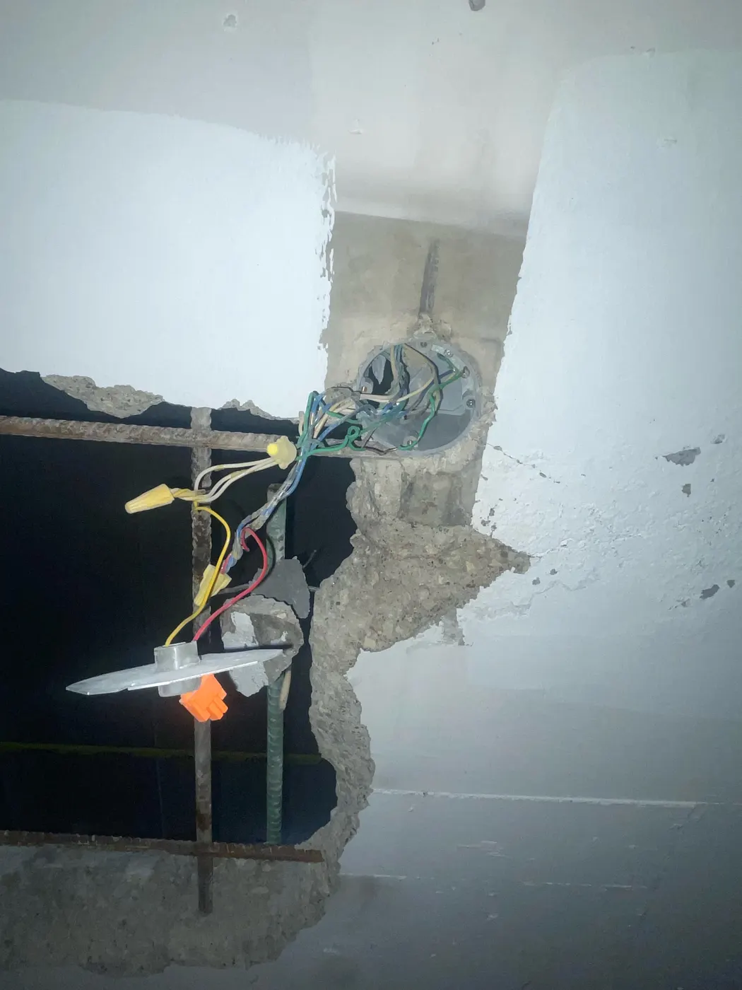 Opened concrete slab exposing parking garage lighting conduit and conductors during repair in Toronto.