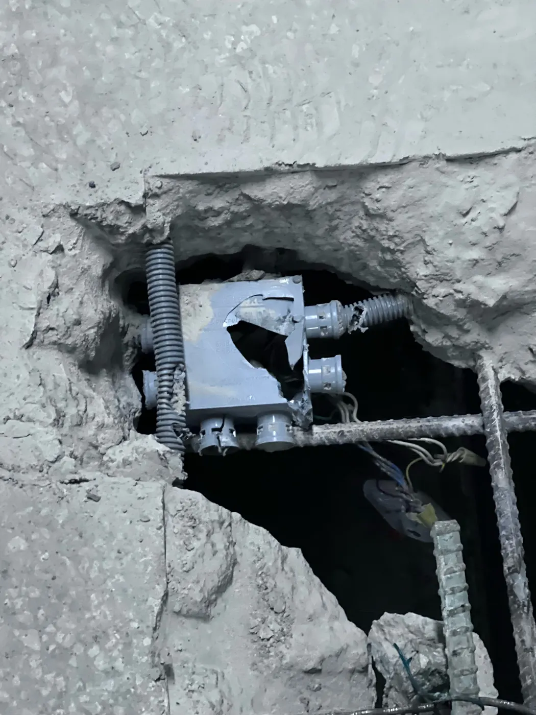Damaged embedded electrical conduit exposed in a Toronto parking garage concrete slab.