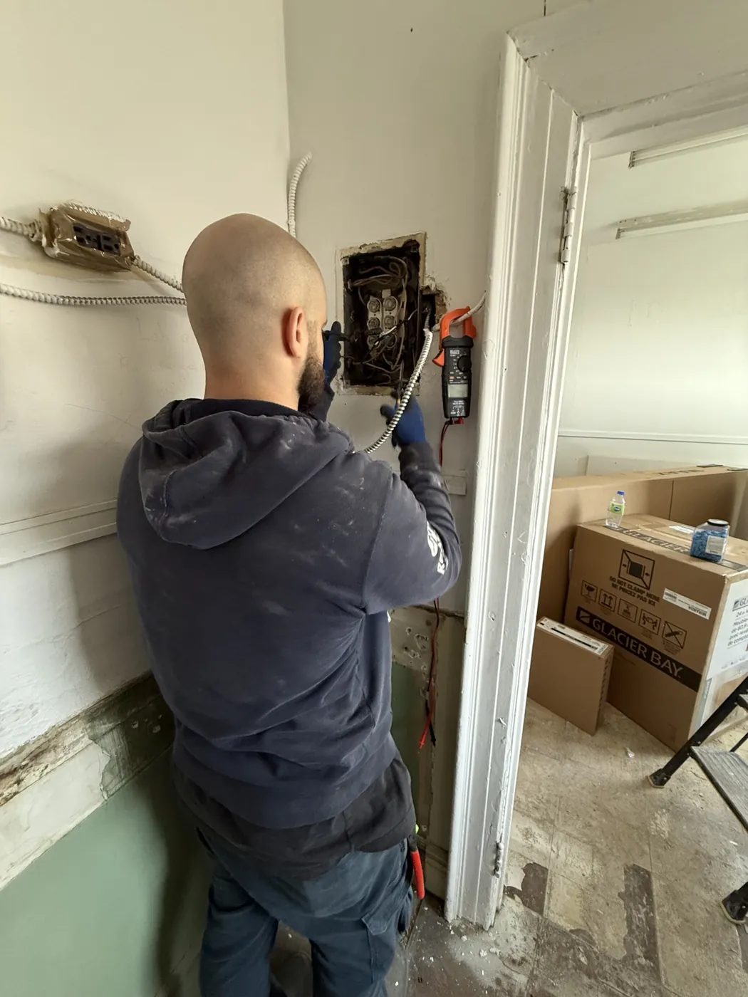 Portman Electric electrician inspecting old fuse panel wiring in a Toronto commercial tenant space.