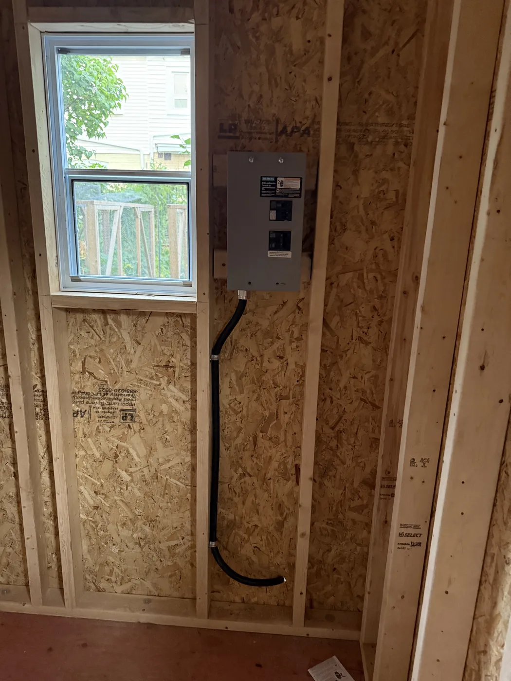 Electrical panel and rough-in wiring in an open framed wall during a renovation