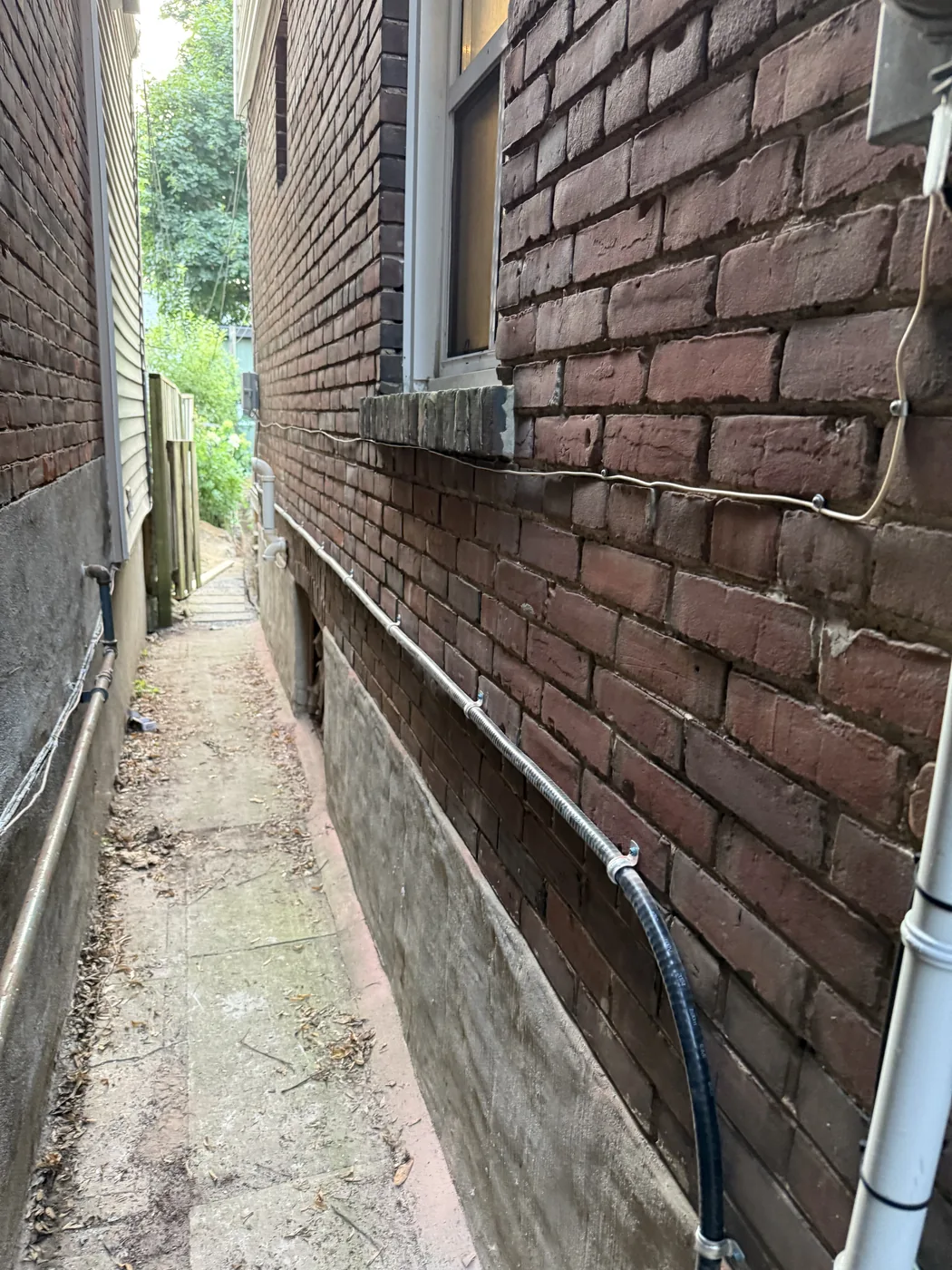 TECK cable feeding a detached garage, run along the side of a brick house and clipped to the wall, installed by Portman Electric